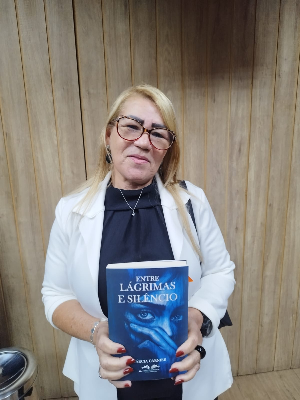 Leitora segurando o livro Entre Lágrimas e Silêncio