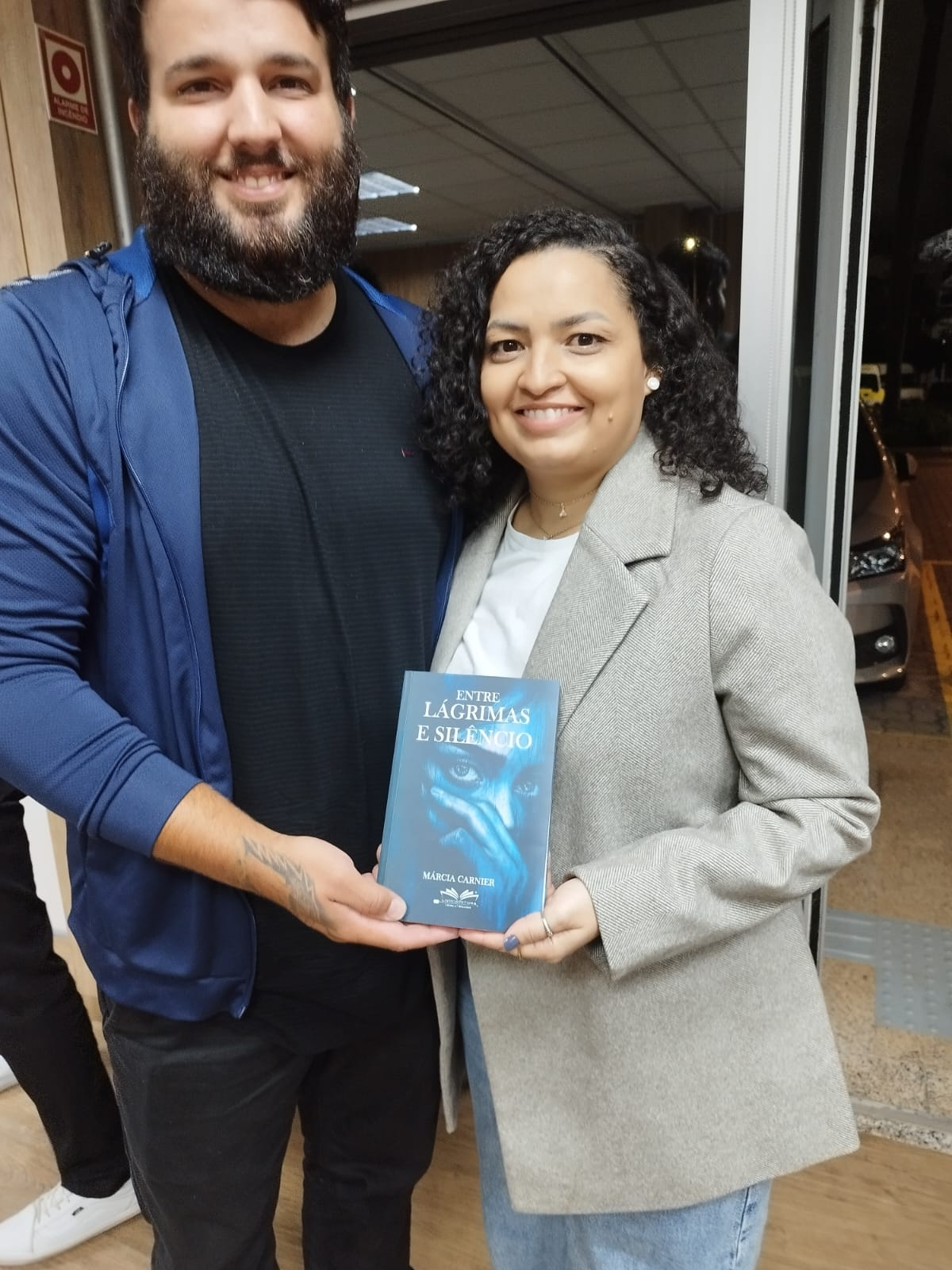 Casal segurando o livro Entre Lágrimas e Silêncio